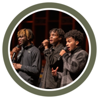 Photo of three students on stage at the WWU Church singing into microphones